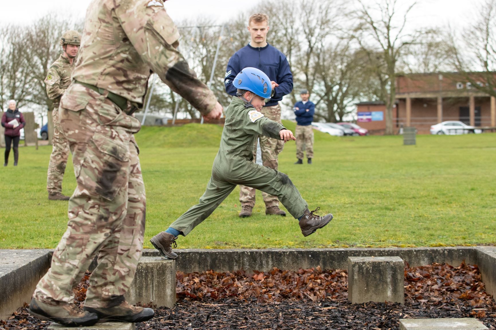 Jacob leaps across obstacle course with RAF personnel.
